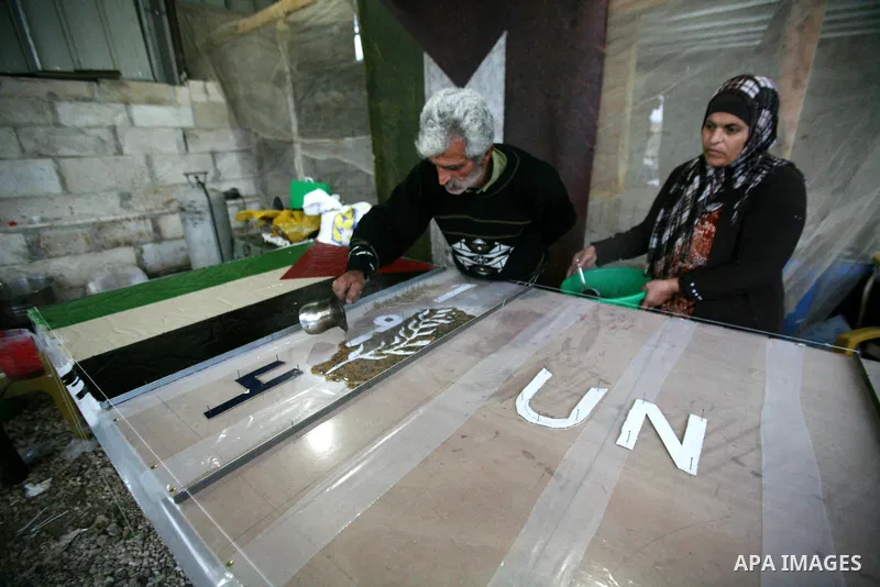 Farmer Suhail Brighit paints a Palestinian flag with the United Nations "UN" flag in support Palestinian President Mahmoud Abbas's step to seek non-member observer status for Palestine at the United Nations, in the West...