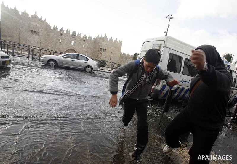Palestinians cross a flooded street outside al-Aqsa Mosque compound, Islam's third holiest, in the old city of Jerusalem on November 12, 2012. Photo by Mahfouz Abu Turk