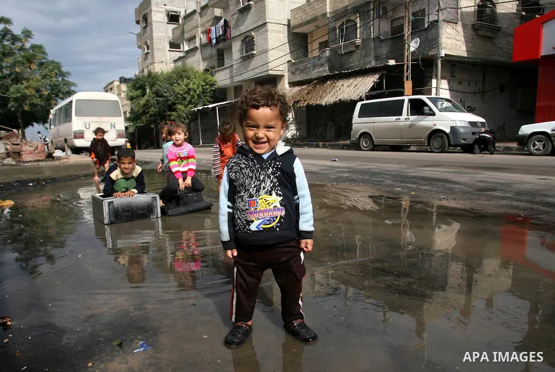 Palestinian children enjoy themselves with water during cold weather and low temperature in the southern Gaza Strip town of Rafah on Nov. 13, 2012. Photo by Eyad Al Baba