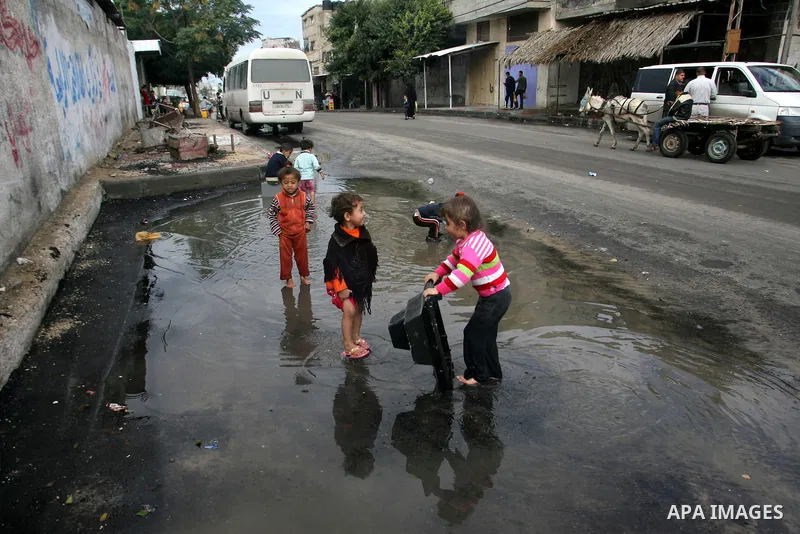 Palestinian children enjoy themselves with water during cold weather and low temperature in the southern Gaza Strip town of Rafah on Nov. 13, 2012. Photo by Eyad Al Baba