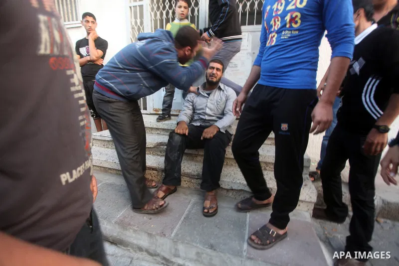 Palestinians gather after extinguish fire from the car of Ahmed Jaabari, head of the military wing of the Hamas movement, the Ezzedin Qassam Brigades, after it was hit by an Israeli air strike in Gaza City on November 14...