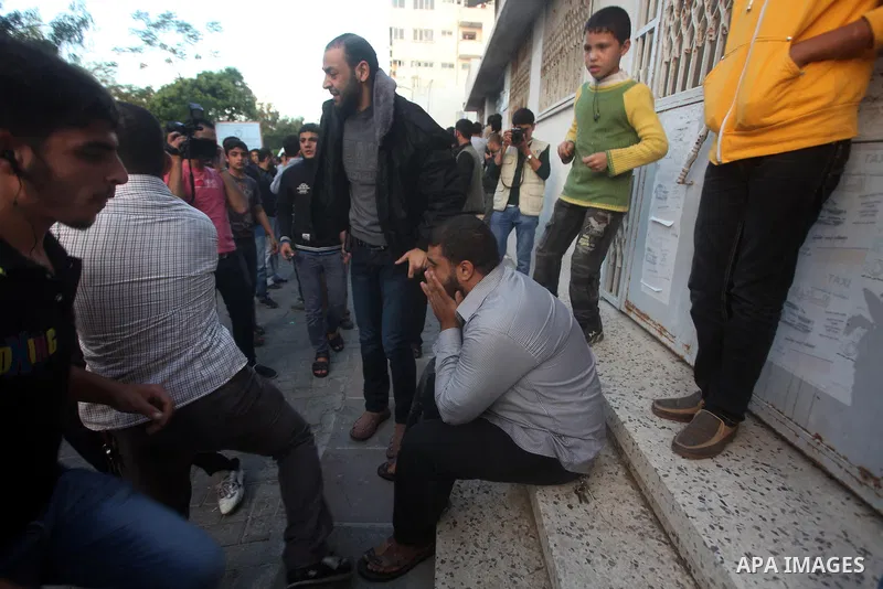 Palestinians gather after extinguish fire from the car of Ahmed Jaabari, head of the military wing of the Hamas movement, the Ezzedin Qassam Brigades, after it was hit by an Israeli air strike in Gaza City on November 14...