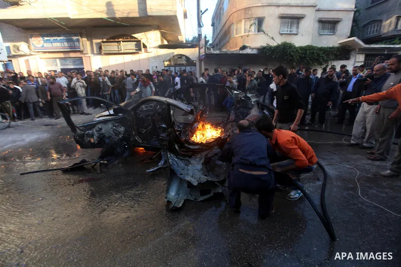 Palestinians extinguish fire from the car of Ahmed Jaabari, head of the military wing of the Hamas movement, the Ezzedin Qassam Brigades, after it was hit by an Israeli air strike in Gaza City on November 14, 2012. The t...