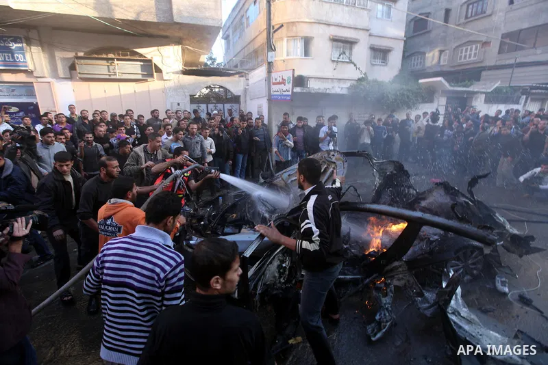 Palestinians extinguish fire from the car of Ahmed Jaabari, head of the military wing of the Hamas movement, the Ezzedin Qassam Brigades, after it was hit by an Israeli air strike in Gaza City on November 14, 2012. The t...