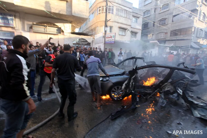 Palestinians extinguish fire from the car of Ahmed Jaabari, head of the military wing of the Hamas movement, the Ezzedin Qassam Brigades, after it was hit by an Israeli air strike in Gaza City on November 14, 2012. The t...