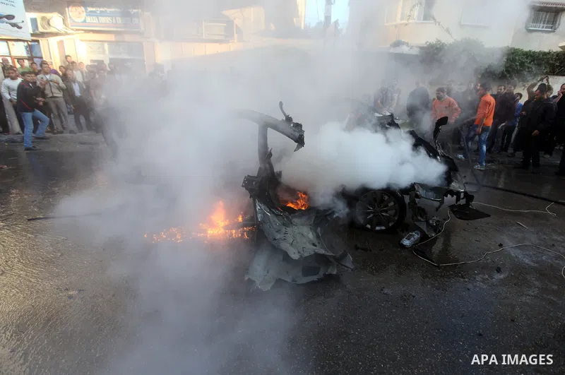 Palestinians extinguish fire from the car of Ahmed Jaabari, head of the military wing of the Hamas movement, the Ezzedin Qassam Brigades, after it was hit by an Israeli air strike in Gaza City on November 14, 2012. The t...