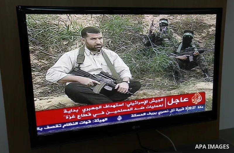 Palestinians watch T.V news of al-Jazeera at their work in Gaza city November 14, 2012. Israel killed the military commander of the Islamist group Hamas in a missile strike on the Gaza Strip on Wednesday and launched air...