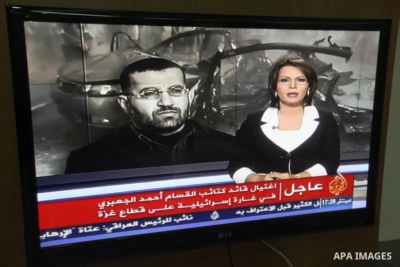 Palestinians watch T.V news of al-Jazeera at their work in Gaza city November 14, 2012. Israel killed the military commander of the Islamist group Hamas in a missile strike on the Gaza Strip on Wednesday and launched air...