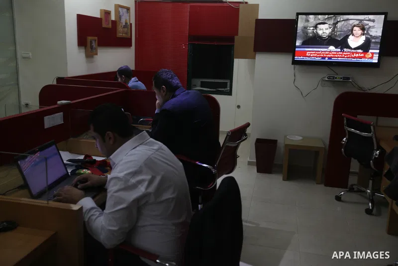 Palestinians watch T.V news of al-Jazeera at their work in Gaza city November 14, 2012. Israel killed the military commander of the Islamist group Hamas in a missile strike on the Gaza Strip on Wednesday and launched air...