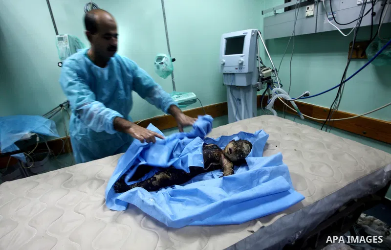 A Palestinian medic stands near a body of a girl died after an Israeli air strike in Gaza City November 14, 2012. Israel killed the military commander of the Islamist group Hamas in a missile strike on the Gaza Strip on...