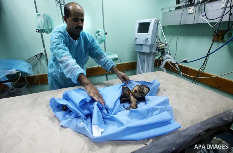 A Palestinian medic stands near a body of a girl died after an Israeli air strike in Gaza City November 14, 2012. Israel killed the military commander of the Islamist group Hamas in a missile strike on the Gaza Strip on...