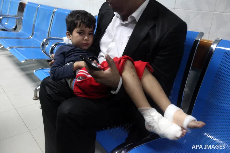 A Palestinian man carries his wounded son into the treatment room of al-Shifa hospital following an Israeli airstrike in Gaza City, Wednesday, Nov. 14, 2012. The Israeli military said its assassination of the Hamas milit...