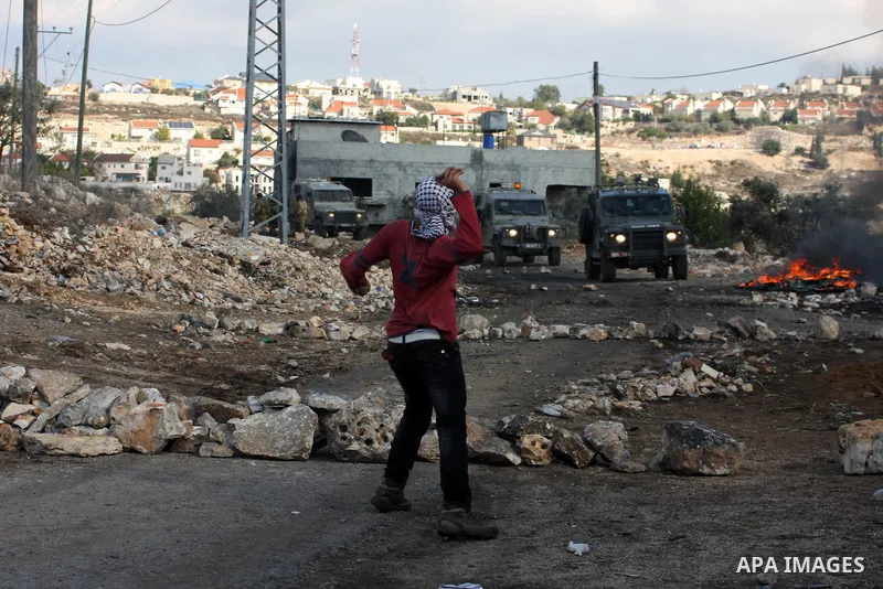 A Palestinian protester throws a stone towards Israeli troops during clashes in the village of Kafr Qaddum near the West Bank city of Nablus on November 14, 2012. Palestinians held rallies across the West Bank, a day bef...