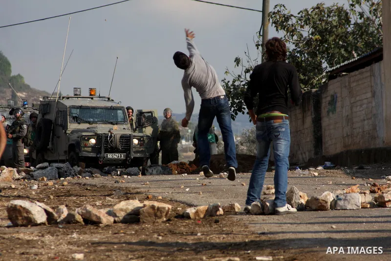 A Palestinian protester throws a stone towards Israeli troops during clashes in the village of Kafr Qaddum near the West Bank city of Nablus on November 14, 2012. Palestinians held rallies across the West Bank, a day bef...