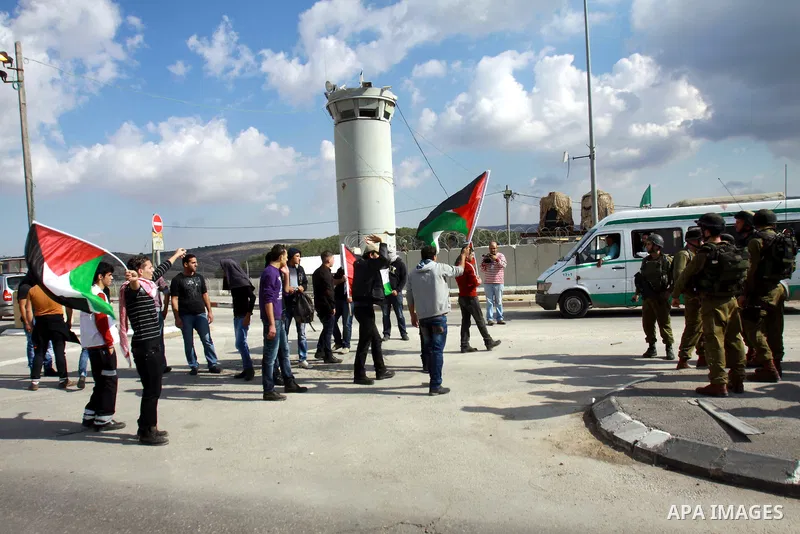 Palestinian activists hold a flag in front of Israeli soldiers at Hawara checkpoint near the West Bank city of Nablus November 14, 2012. Demonstrators against Israeli occupation of the West Bank repeatedly blocked main r...