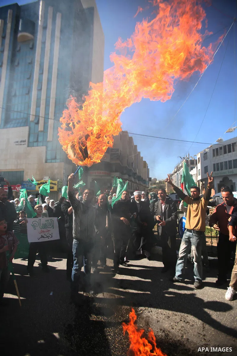 Palestinian Hamas supporters burn the Israeli and the U.S flags during a demonstration in support of the people of the Gaza Strip and against Israeli air strikes in the West Bank city of Hebron on November 15, 2012 . Sev...