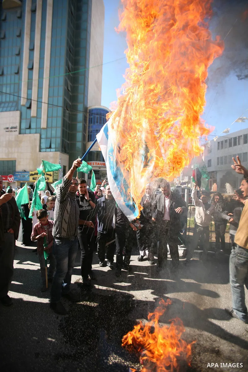 Palestinian Hamas supporters burn the Israeli and the U.S flags during a demonstration in support of the people of the Gaza Strip and against Israeli air strikes in the West Bank city of Hebron on November 15, 2012 . Sev...