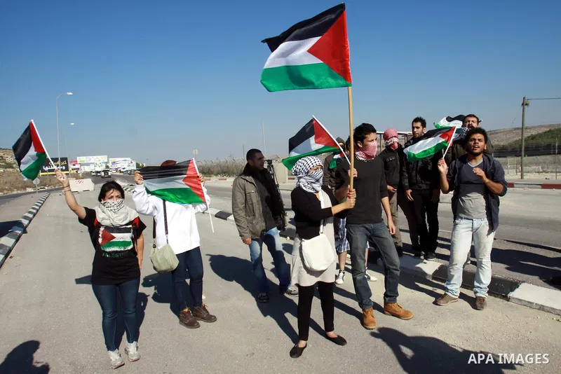 Palestinian activists hold their national flags while they block a road leading to Huwwara checkpoint near the West Bank city of Nablus during a demonstration in support of the people of the Gaza Strip and against Israel...