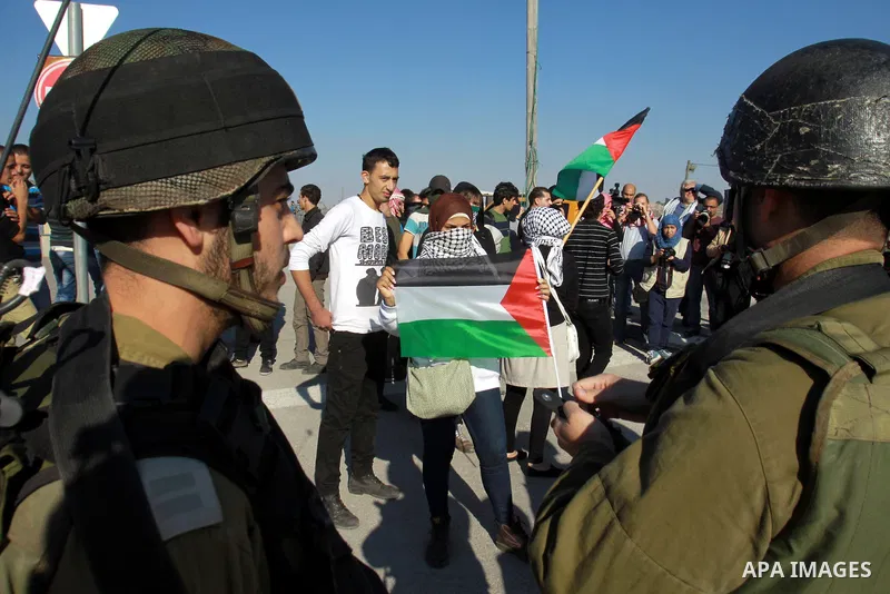 Palestinian activists hold their national flags while they block a road leading to Huwwara checkpoint near the West Bank city of Nablus during a demonstration in support of the people of the Gaza Strip and against Israel...