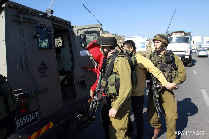 Israeli soldiers detain Palestinian youths in a protest to block a road leading to Huwwara checkpoint near the West Bank city of Nablus during a demonstration in support of the people of the Gaza Strip and against Israel...