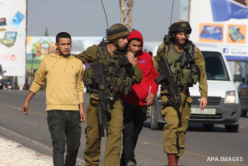 Israeli soldiers detain Palestinian youths in a protest to block a road leading to Huwwara checkpoint near the West Bank city of Nablus during a demonstration in support of the people of the Gaza Strip and against Israel...