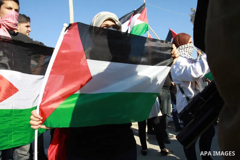 Palestinian activists hold their national flags while they block a road leading to Huwwara checkpoint near the West Bank city of Nablus during a demonstration in support of the people of the Gaza Strip and against Israel...