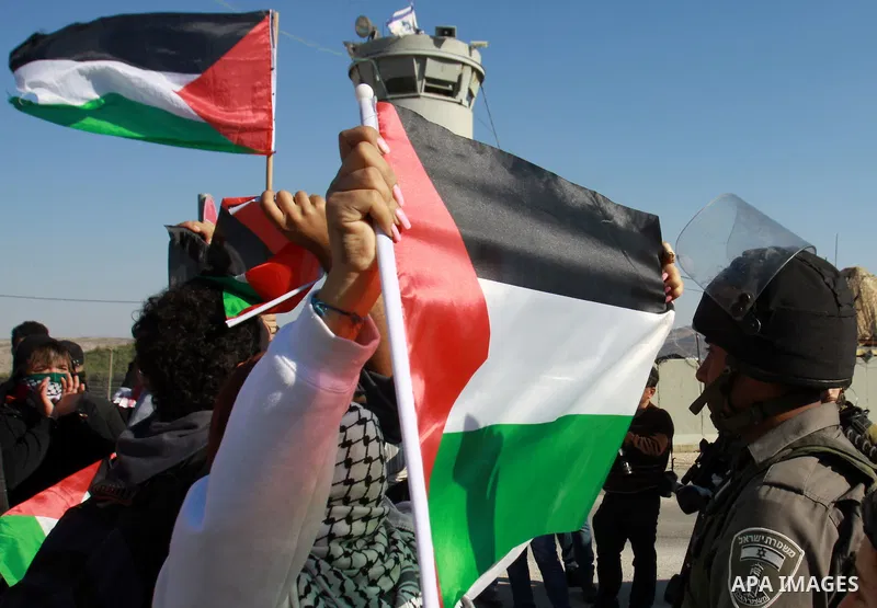 Palestinian activists hold their national flags while they block a road leading to Huwwara checkpoint near the West Bank city of Nablus during a demonstration in support of the people of the Gaza Strip and against Israel...