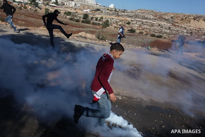 A Palestinian protester returns a tear gas canister toward Israeli troops during clashes against Israel's operations in Gaza Strip, outside Ofer, an Israeli military prison near the West Bank city of Ramallah, Thursday,...