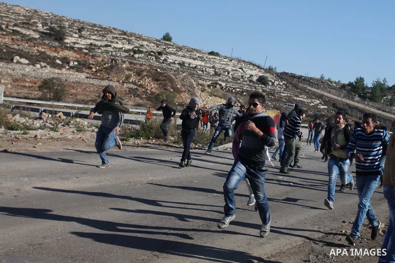 Palestinian demonstrators run cover from tear gas during clashes against Israel's operations in Gaza Strip, outside Ofer, an Israeli military prison near the West Bank city of Ramallah, Thursday, Nov. 15, 2012. Meanwhile...