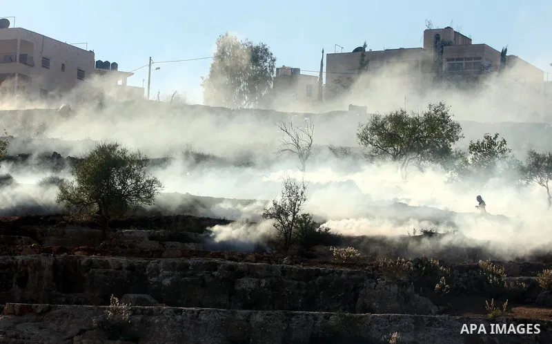 A Palestinian demonstrator runs through a cloud of tear gas during clashes against Israel's operations in Gaza Strip, outside Ofer, an Israeli military prison near the West Bank city of Ramallah, Thursday, Nov. 15, 2012....