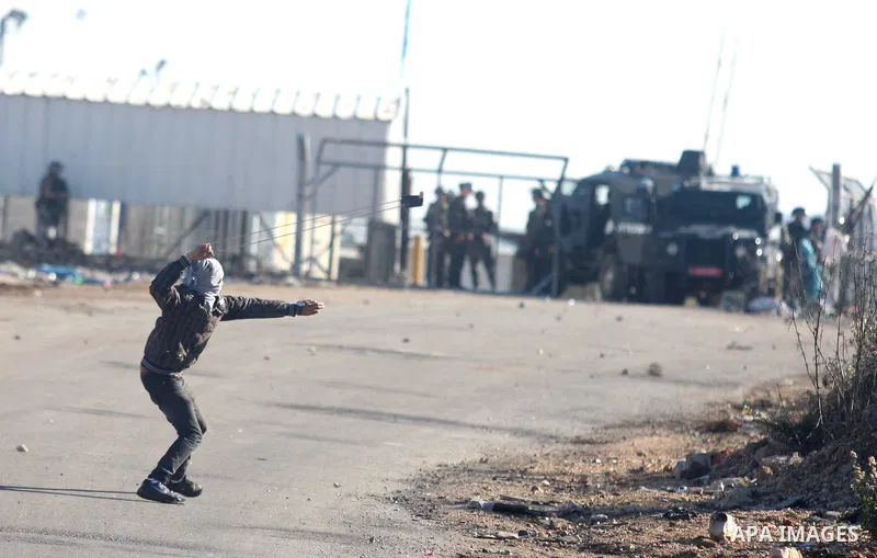 A Palestinian protester throws stones at Israeli troops during clashes against Israel's operations in Gaza Strip, outside Ofer, an Israeli military prison near the West Bank city of Ramallah, Thursday, Nov. 15, 2012. Mea...