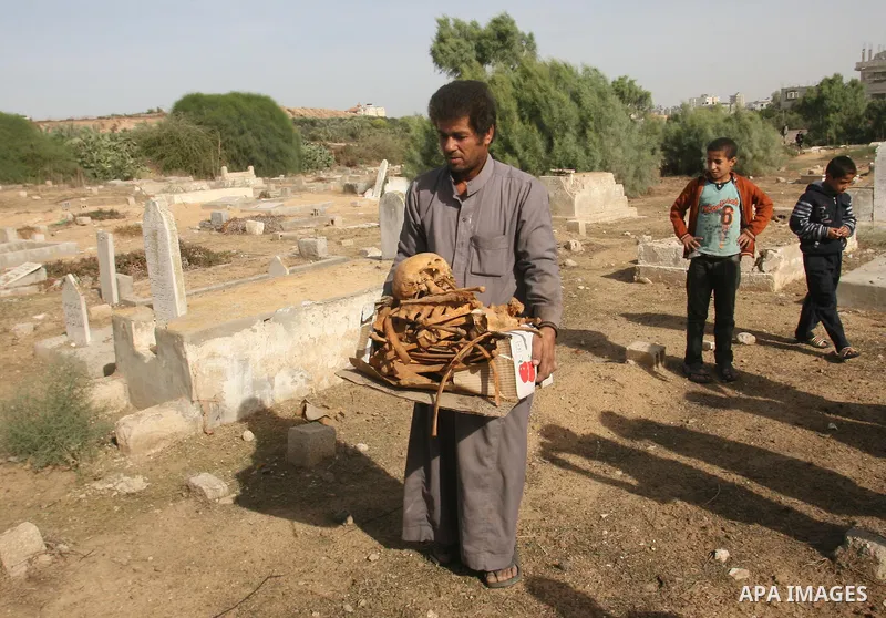 A Palestinian man carries bones from a grave after an Israeli airstrike on a cemetery in the southern of Gaza strip town of Rafah on November 16, 2012. Missiles continue to be fired on Israeli targets by Palestinian mili...