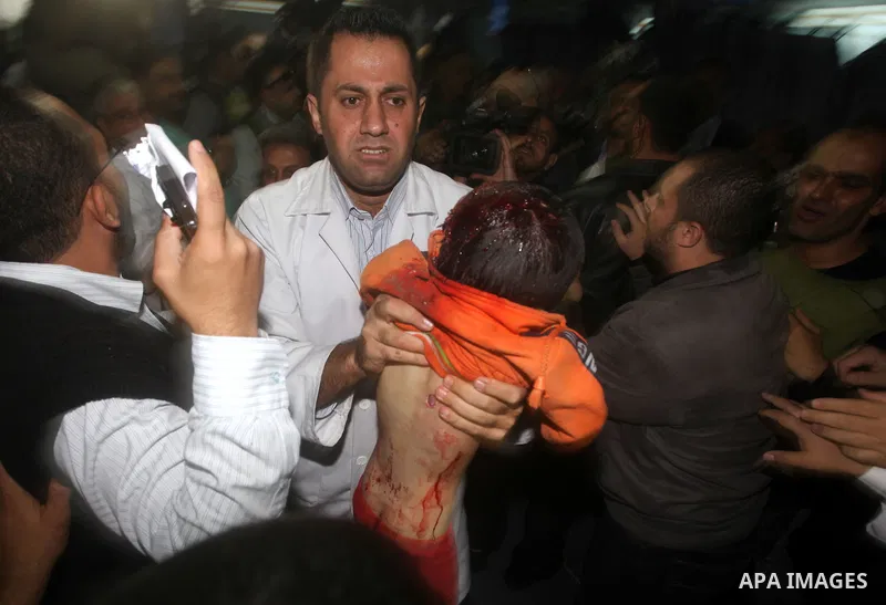 A Palestinian doctor carries the body of a baby boy who was killed in an Israeli air strike, during the visit by the Palestinian Prime Minister in the Gaza Strip Ismail Haniya and Egyptian Prime Minister Hisham Qandil (b...