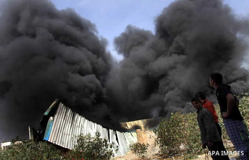 Palestinians stand near a factory which according to Palestinians was hit by an Israeli air strike in Gaza November 16, 2012. Egyptian Prime Minister Hisham Kandil arrived in the Gaza Strip on Friday to show solidarity w...