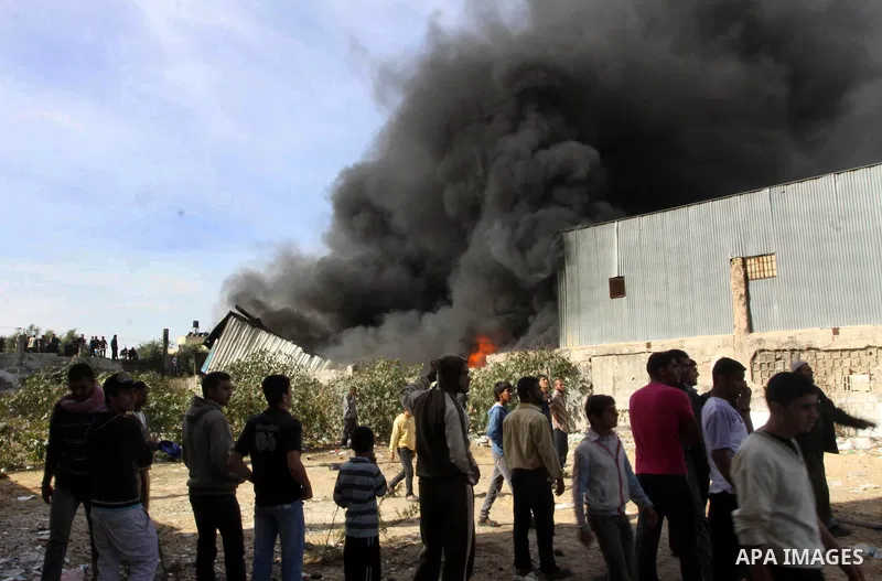 Palestinians stand near a factory which according to Palestinians was hit by an Israeli air strike in Gaza November 16, 2012. Egyptian Prime Minister Hisham Kandil arrived in the Gaza Strip on Friday to show solidarity w...