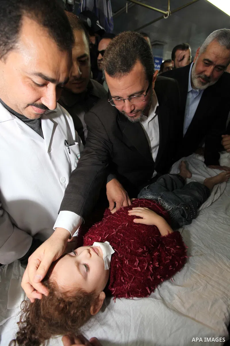 Palestinian Prime Minister in the Gaza Strip Ismail Haniyeh and Egypt's Prime Minister Hisham Kandil hold the hand of a Child, who was injured during an Israeli strike, during their visit to a hospital in Gaza City Novem...