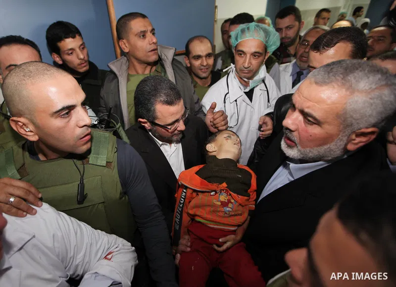 Palestinian Prime Minister in the Gaza Strip Ismail Haniyeh and Egypt's Prime Minister Hisham Kandil touch the body of a Palestinian boy, who was killed in an Israeli air strike, during a visit to a hospital in Gaza City...