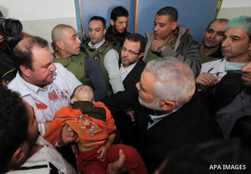 Palestinian Prime Minister in the Gaza Strip Ismail Haniyeh and Egypt's Prime Minister Hisham Kandil touch the body of a Palestinian boy, who was killed in an Israeli air strike, during a visit to a hospital in Gaza City...