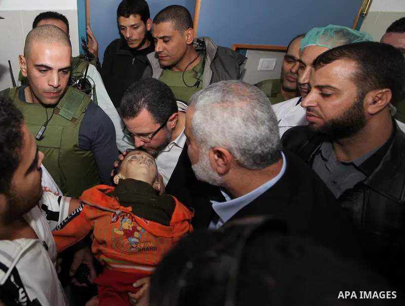 Palestinian Prime Minister in the Gaza Strip Ismail Haniyeh and Egypt's Prime Minister Hisham Kandil touch the body of a Palestinian boy, who was killed in an Israeli air strike, during a visit to a hospital in Gaza City...