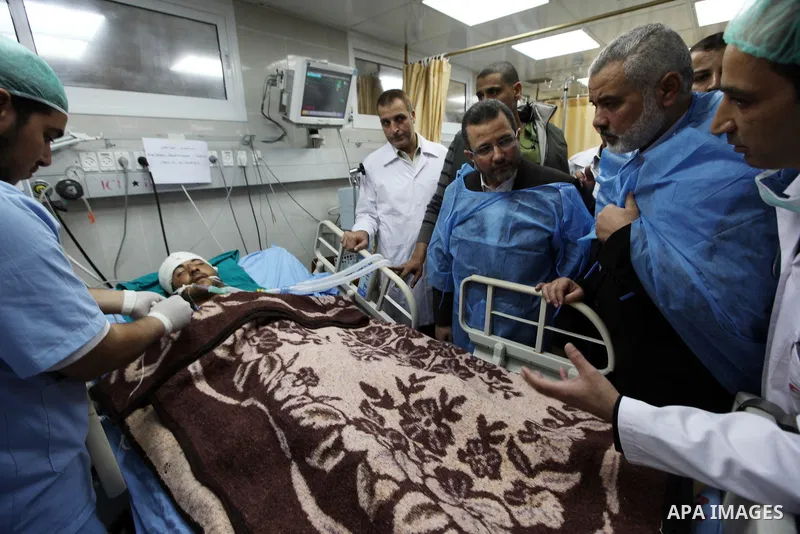 Palestinian Prime Minister in the Gaza Strip Ismail Haniyeh and Egypt's Prime Minister Hisham Kandil hold the hand of a patient, who was injured during an Israeli strike, during their visit to a hospital in Gaza City Nov...