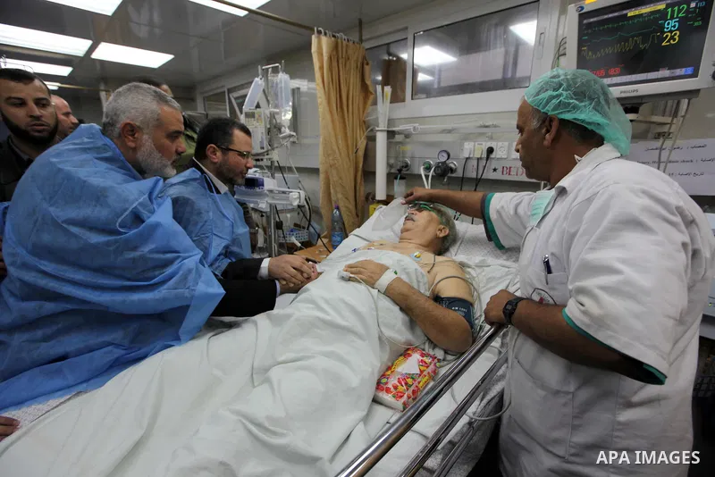 Palestinian Prime Minister in the Gaza Strip Ismail Haniyeh and Egypt's Prime Minister Hisham Kandil hold the hand of a patient, who was injured during an Israeli strike, during their visit to a hospital in Gaza City Nov...