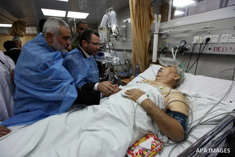 Palestinian Prime Minister in the Gaza Strip Ismail Haniyeh and Egypt's Prime Minister Hisham Kandil hold the hand of a patient, who was injured during an Israeli strike, during their visit to a hospital in Gaza City Nov...