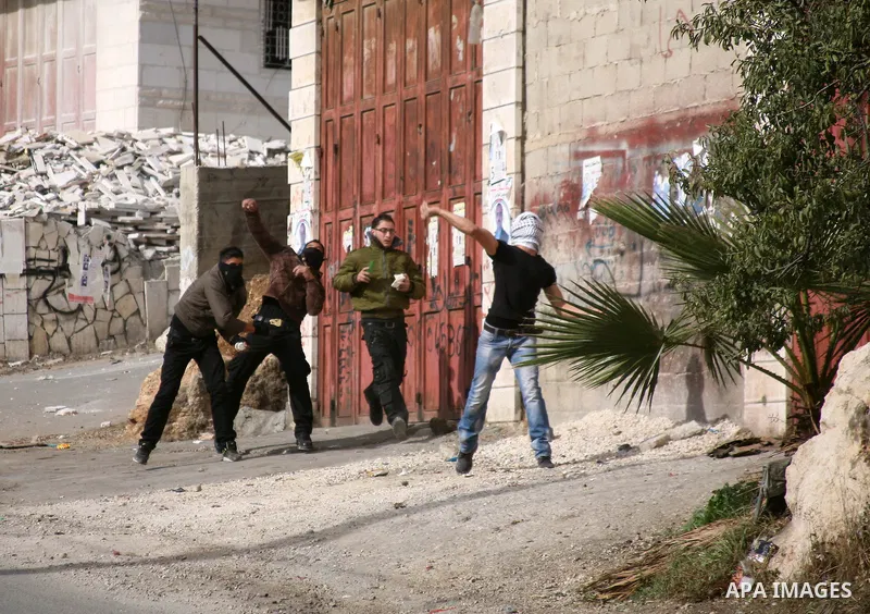 Palestinian demonstrators throw stones at Israeli troops during clashes following a protest against Israel's operations in Gaza Strip in the village of Beit Ummar near the West Bank city of Hebron on November, 16, 2012....