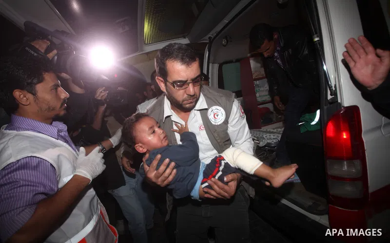 A Palestinian man carries an injured child into the treatment room of Shifa hospital following an Israeli airstrike, in Gaza City, Friday, Nov. 16, 2012. Fierce clashes between Israeli forces and Gaza militants are conti...