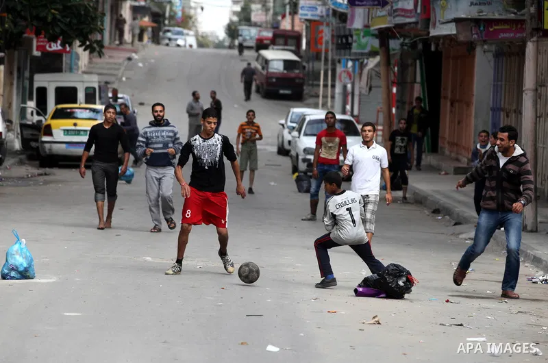 Palestinian youths play football at a street while Israeli aircraft continue the military operation on Gaza strip, in central Gaza city on November 17, 2012. Israeli aircraft bombed Hamas government buildings in Gaza on...