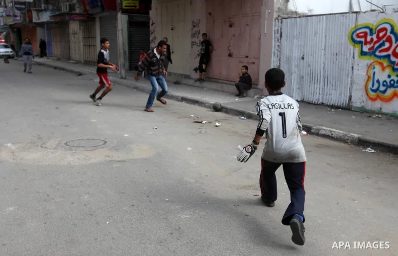 Palestinian youths play football at a street while Israeli aircraft continue the military operation on Gaza strip, in central Gaza city on November 17, 2012. Israeli aircraft bombed Hamas government buildings in Gaza on...