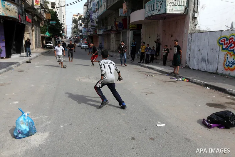 Palestinian youths play football at a street while Israeli aircraft continue the military operation on Gaza strip, in central Gaza city on November 17, 2012. Israeli aircraft bombed Hamas government buildings in Gaza on...