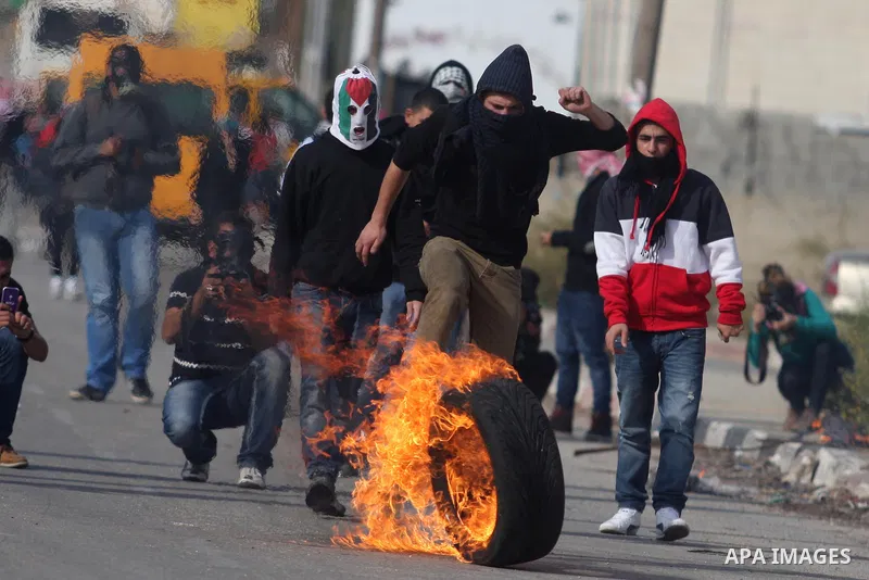 A Palestinian demonstrator kicks a burned tire during clashes against Israel's operations in Gaza Strip, outside Ofer, an Israeli military prison near the West Bank city of Ramallah, Saturday, Nov. 17, 2012. Photo by Iss...