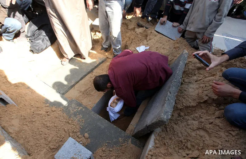 A Palestinian man carries the bodies of two children Tamer Abu Seifan and his 1 year sister Jumana Abu Seifan to the grave during their funeral in Gaza city on November 18, 2012. Israeli war planes hit a Gaza City media...