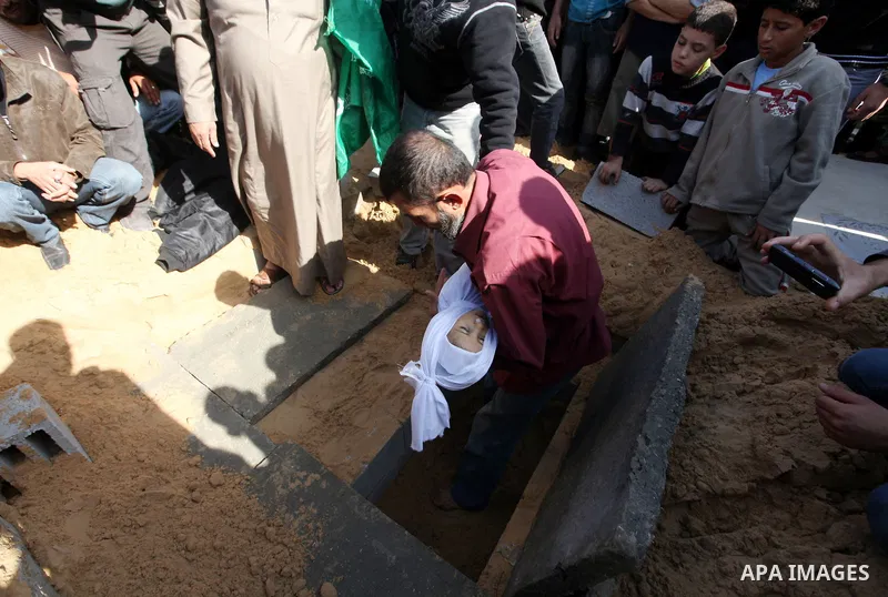 A Palestinian man carries the body of one of children to the grave during their funeral in the northern Gaza Strip November 18, 2012. Two children Jumana Abu Seifan, 18 months old, and her brother Tamer, three and a half...
